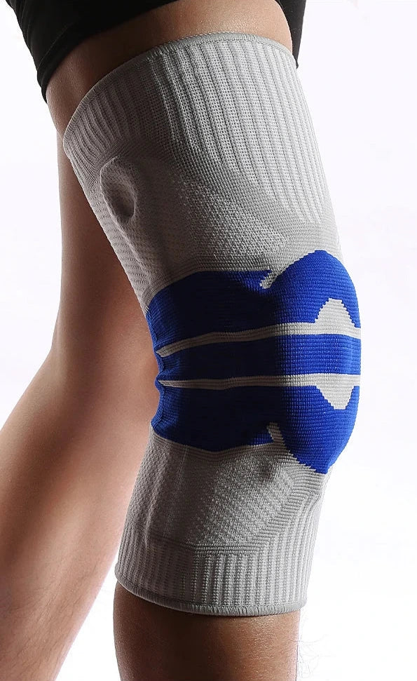 Gray and blue knee brace on a person's knee with a white background
