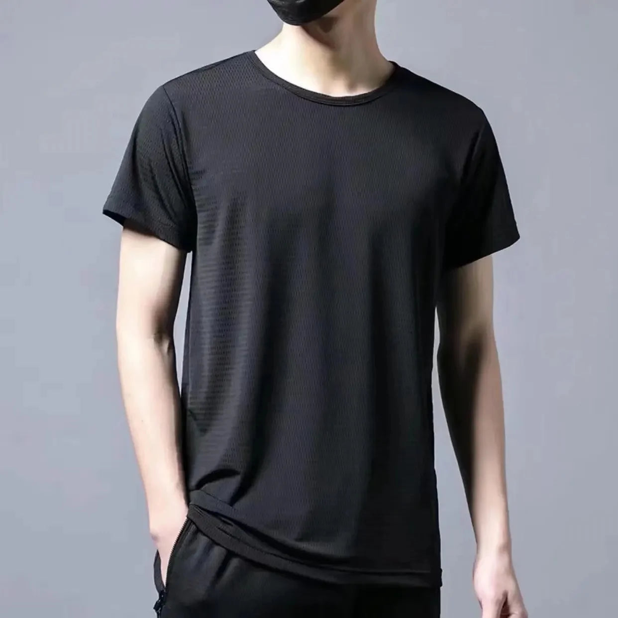 Person wearing a black t-shirt against a gray background