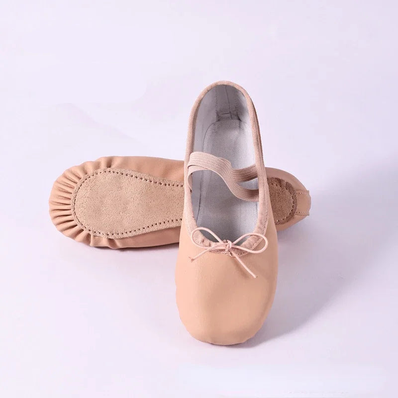 Pair of beige ballet shoes with a bow on a white background