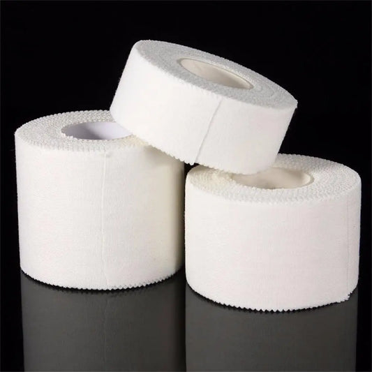Three rolls of white medical tape stacked on a black background