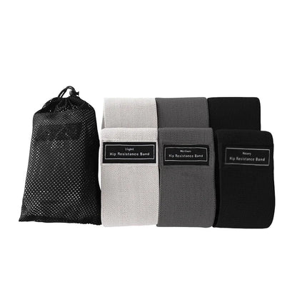 Four resistance bands in black, white, gray, and black with a mesh storage bag on a white background.
