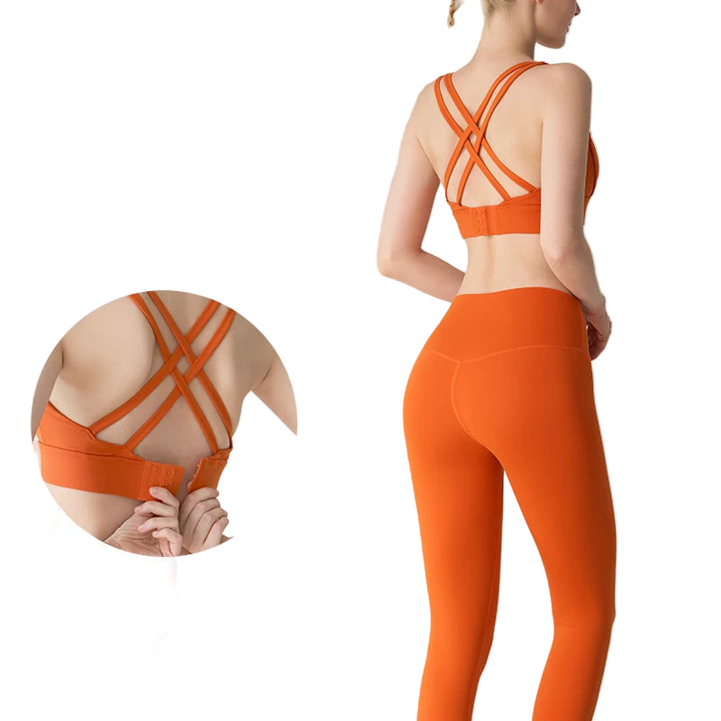Orange sports bra and leggings set with criss-cross straps on a light gray background.